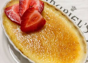 a close-up shot of vanilla bean creme brulee topped with sliced strawberries